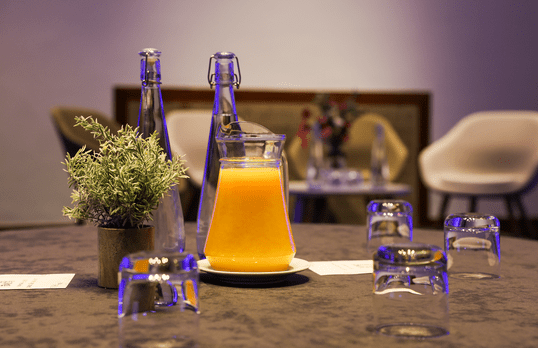 Jug of orange juice and glasses on a table with interview tables in the background
