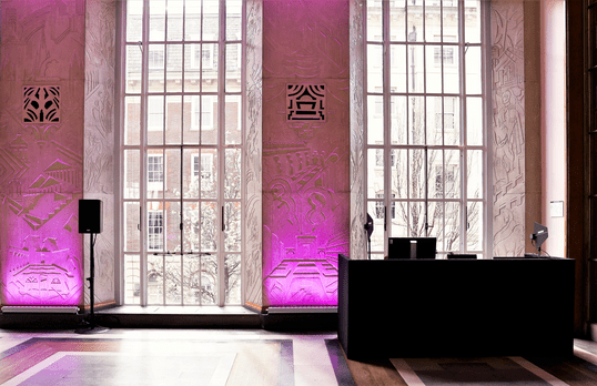 Audio visual set up in the Florence Hall with purple lighting against Art Deco windows