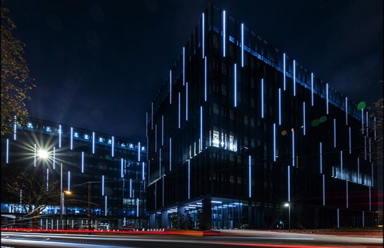 Building at night in darkness highlighted by a series of vertical strip lights. 