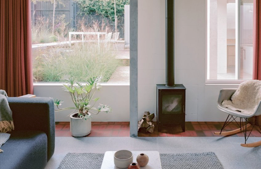 A bright modern interior of a home, with a sofa and small woodburner