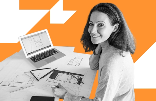 Female architect working smiling at camera as she works on technical drawings