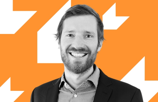 Man smiling to camera with orange background