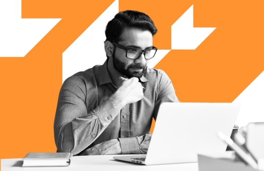 Man working in an office on a laptop with orange background