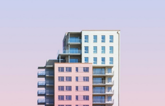 View looking upwards at several multi-storey buildings and blue sky with clouds
