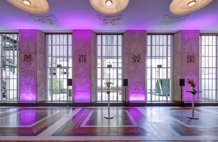 View of floor to ceiling art deco windows with walls bathed in purple uplighters