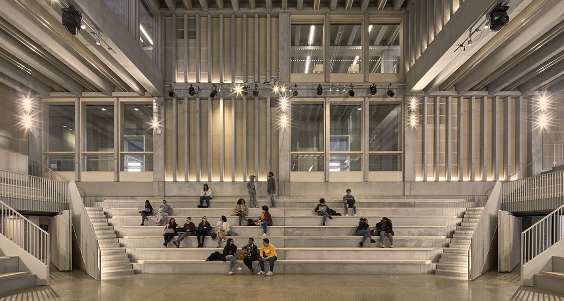 People sitting on grandstand style seating in large atrium spac