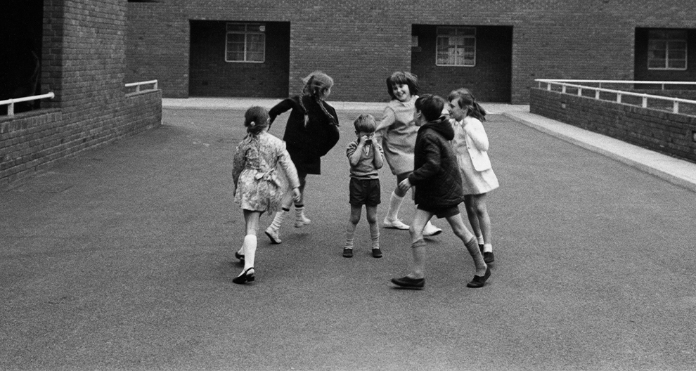 Black and white photograph of children playing in a circle in a brick courtyard, Trafalgar Estate, Greenwich, London